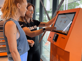 Gym member using a Beetronics touchscreen at self check-in.