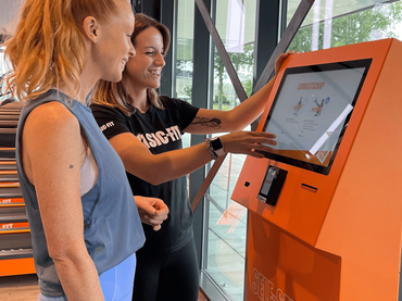 Gym member using a Beetronics touchscreen at self check-in.